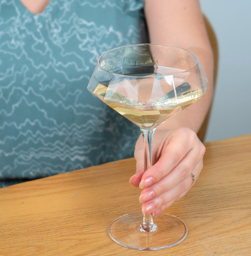 one of the espresso martini glasses in a woman's hand warm light