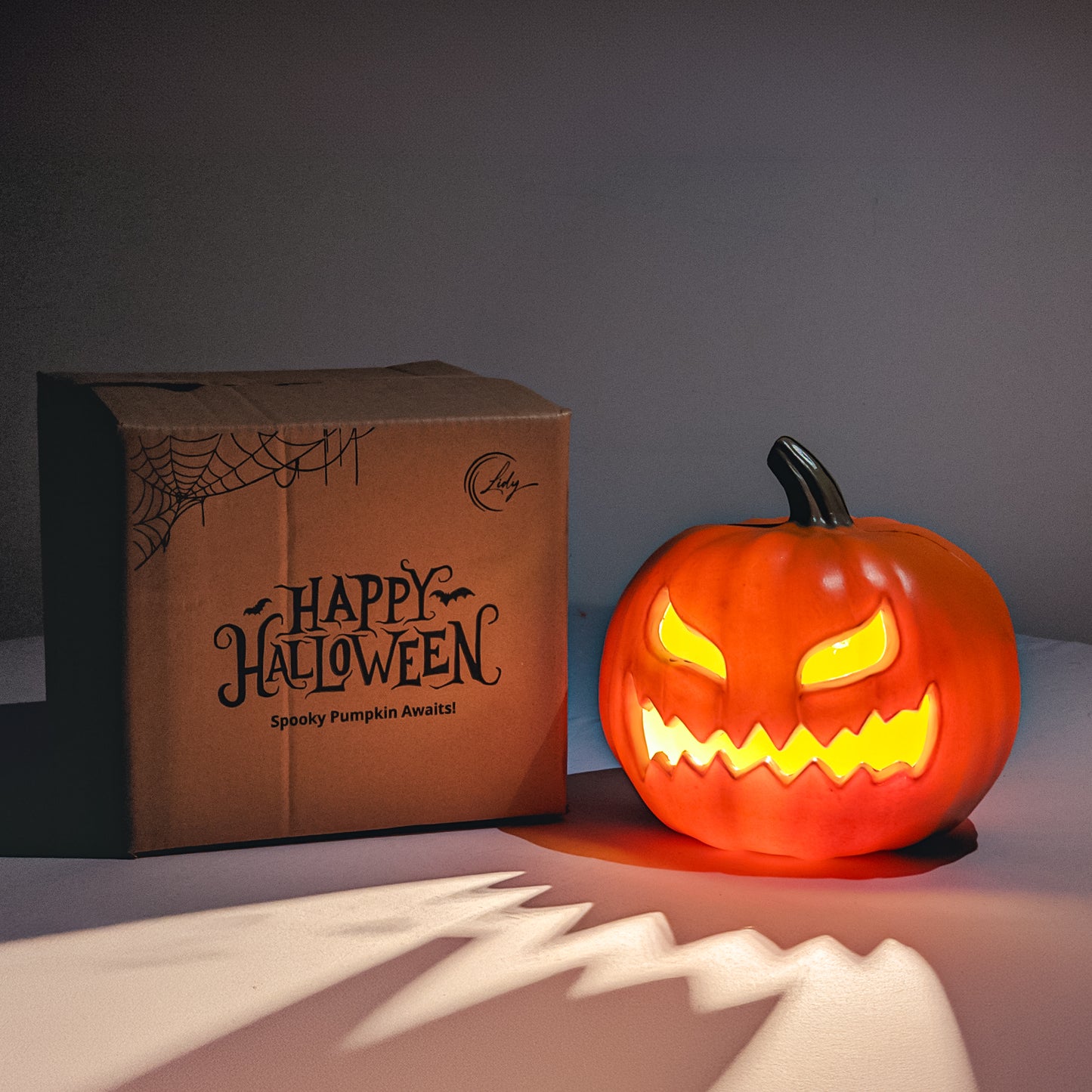 Light-up Halloween pumpkin glowing next to box – spooky decor in the dark