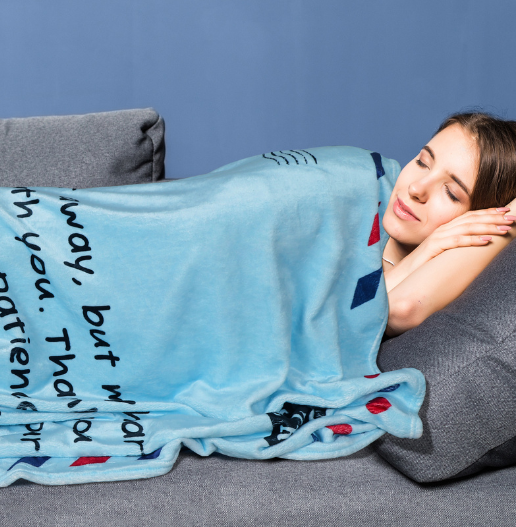 Soft fleece letter blanket for mom covering a young woman resting on a couch – cozy mother’s day blanket full of love and warmth.