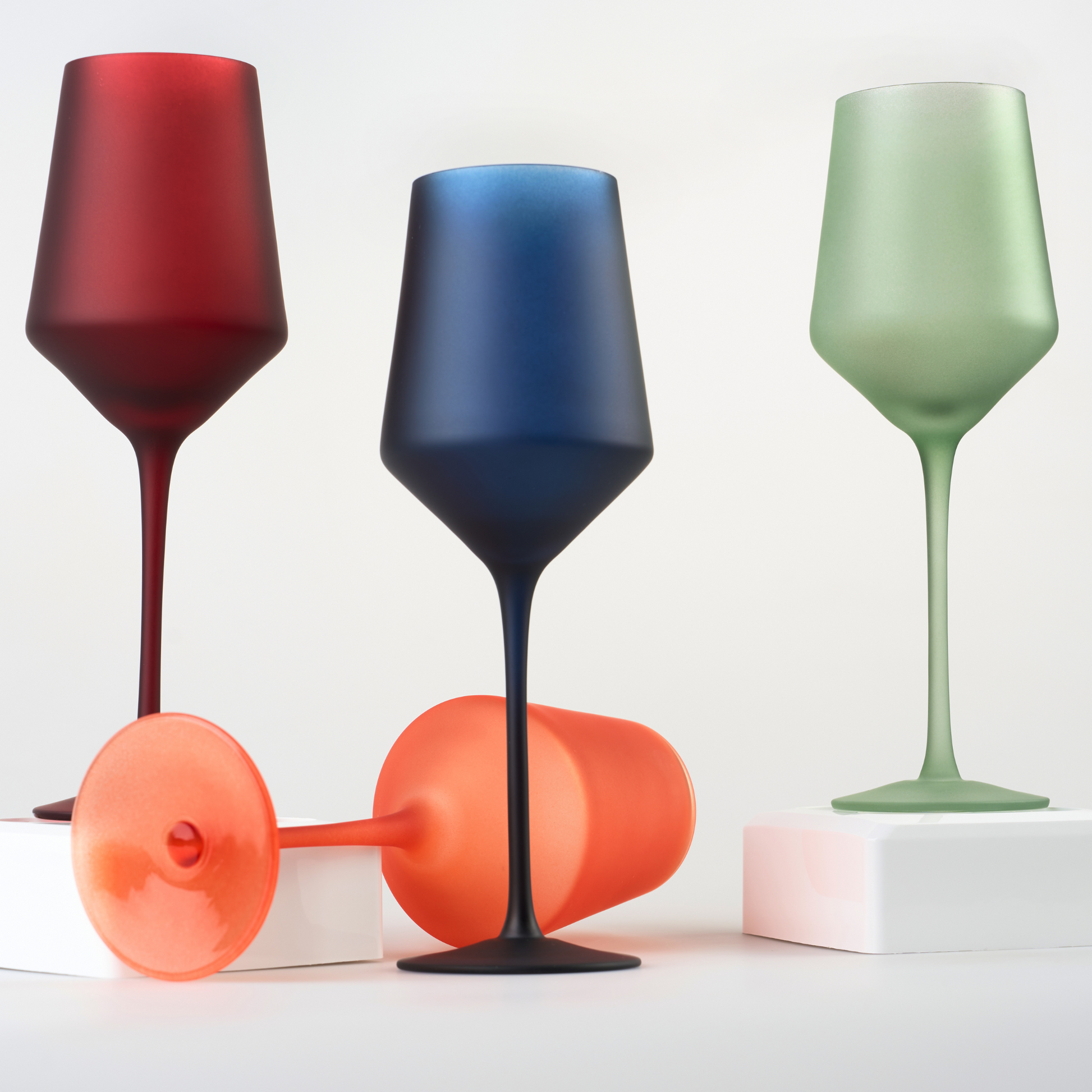 Elegant set of four hand-blown colored wine glasses on a white surface