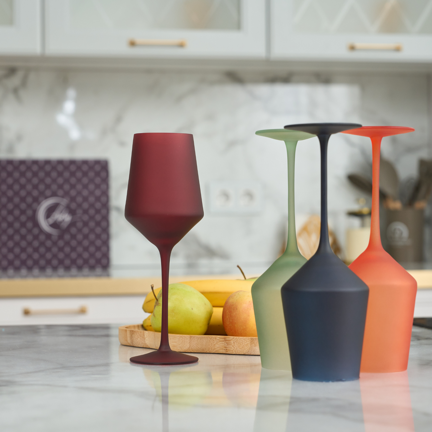 Four multi-colored wine glasses on a marble table, vibrant and ready for a party